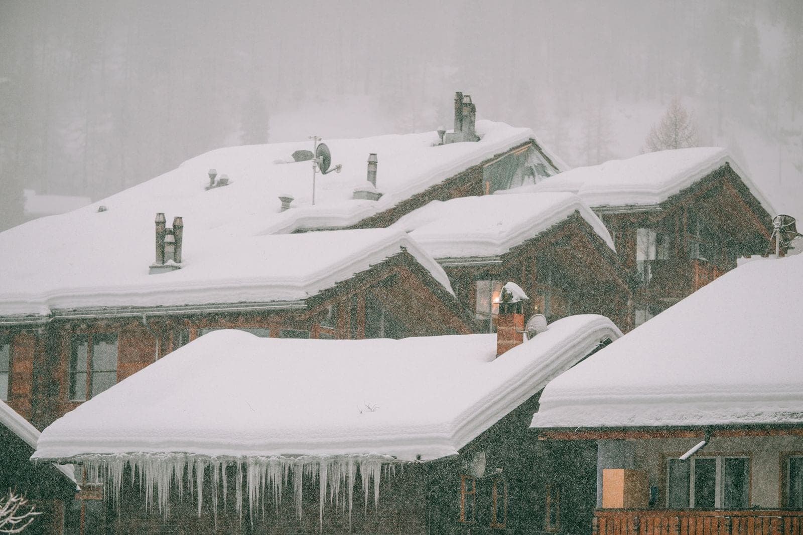 Deep snow and icicles hanging from house roofs during a snowfall