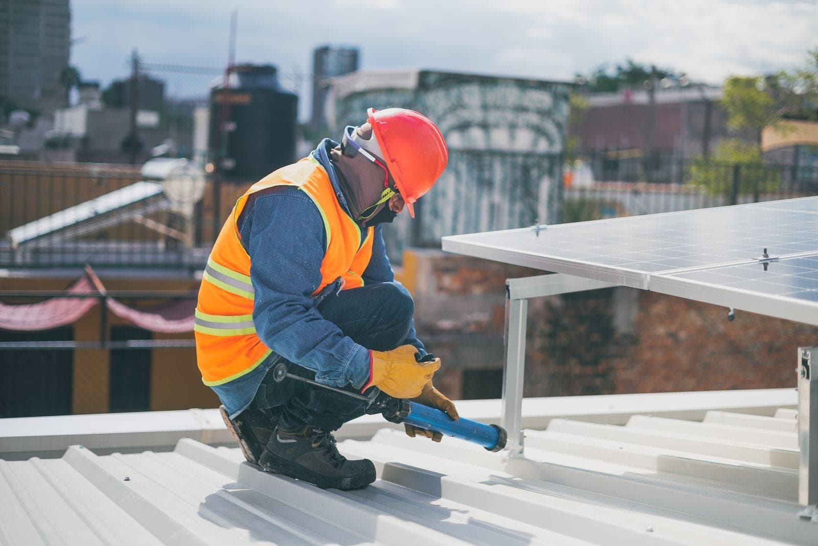 Roofer in a hard hat sealing the seams on a white metal roof