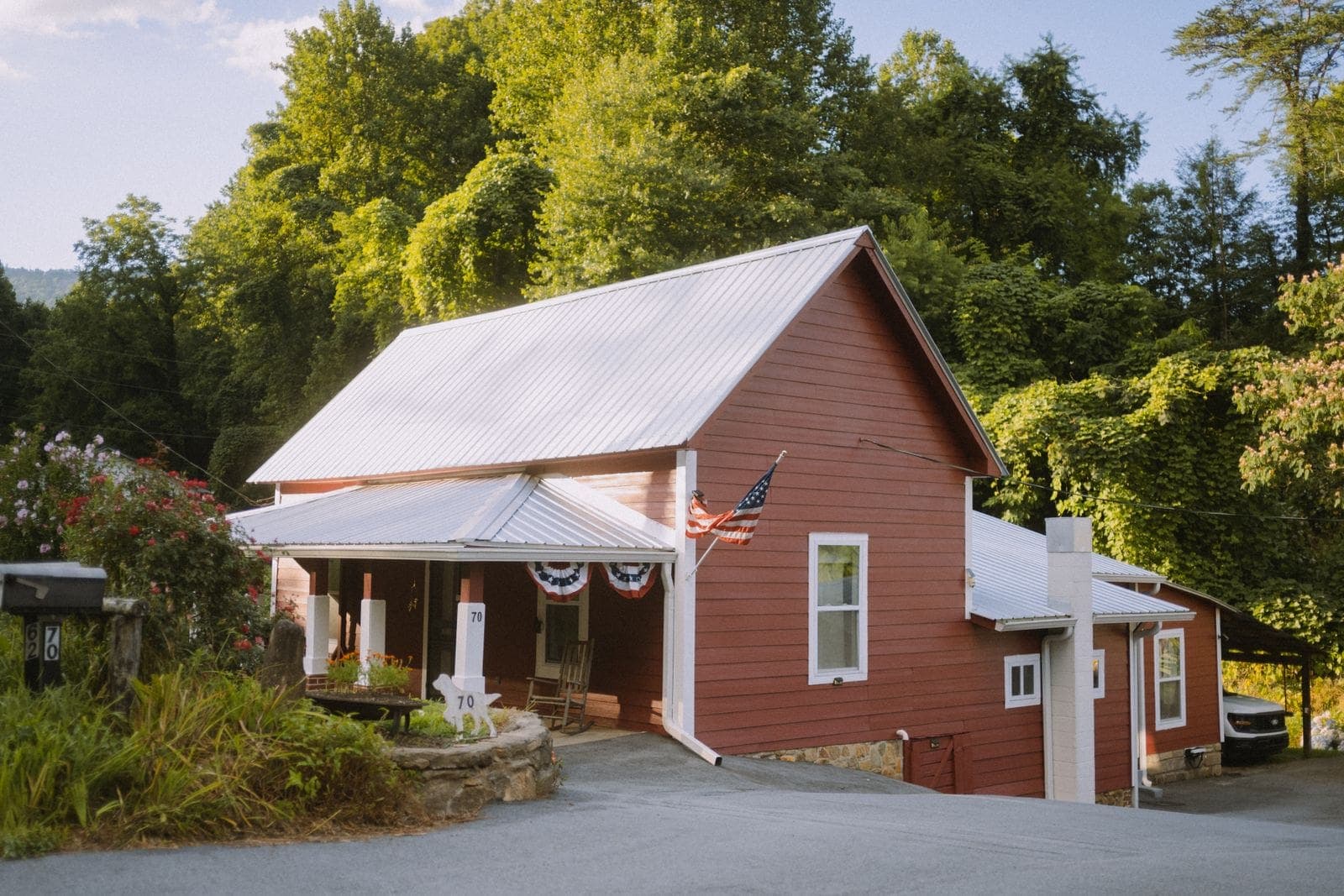 Red house with a silver metal roof among trees