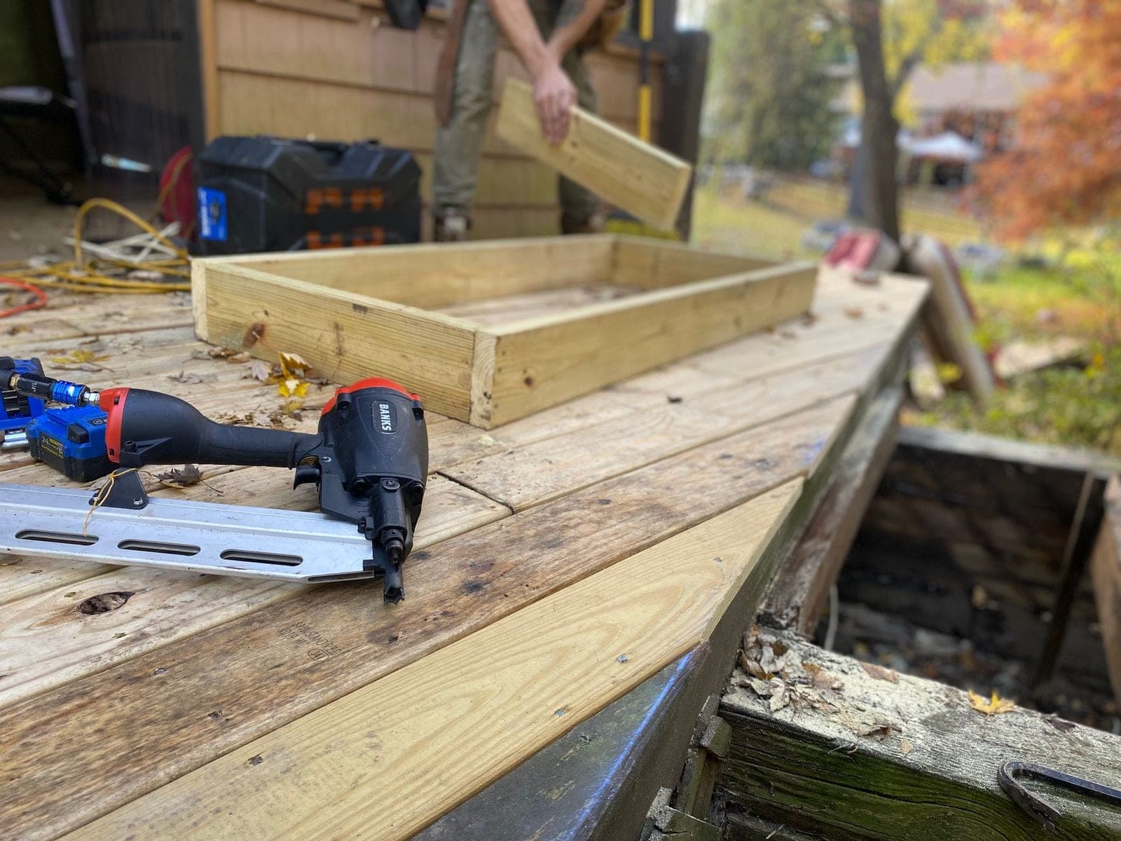 Nail gun and battery tools on a wood deck at a work site